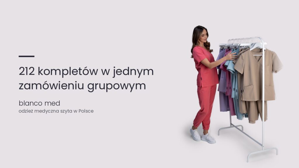 Kobieta w koralowym komplecie medycznym wybiera bluzy medyczne z wieszaka. Zamówienia grupowe odzieży medycznej. Jak zrealizowaliśmy 212 kompletów medycznych w 9 dni roboczych